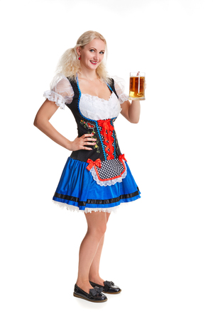 Beautiful young blond girl in dirndl drinks out of oktoberfest beer stein. Isolated on white background. she holds a glass with a drink and smiling. full heightの写真素材