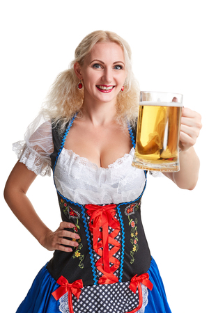 Beautiful young blond girl in dirndl drinks out of oktoberfest beer stein. Isolated on white background. she holds a glass with a drink and smilingの写真素材
