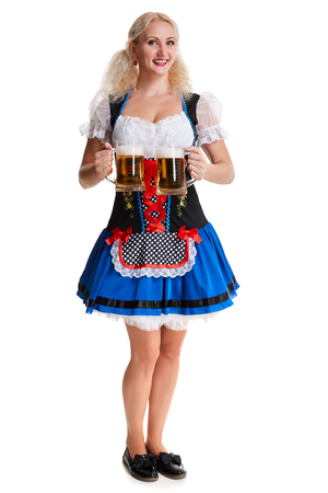 Beautiful young blond girl in dirndl drinks out of oktoberfest beer stein. Isolated on white background. she holds a glass with a drink and smiling. full heightの写真素材