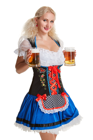 Beautiful young blond girl in dirndl drinks out of oktoberfest beer stein. Isolated on white background. she holds a glass with a drink and smilingの写真素材