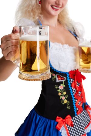 Beautiful young blond girl in dirndl drinks out of oktoberfest beer stein. Isolated on white background. she holds a glass with a drink and smiling. close-upの写真素材