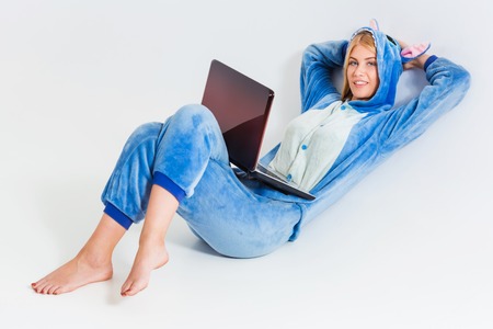 girl in pajamas with a laptop lying on the floor. studying or doing online shopping. work from home. Satisfied and smilingの写真素材