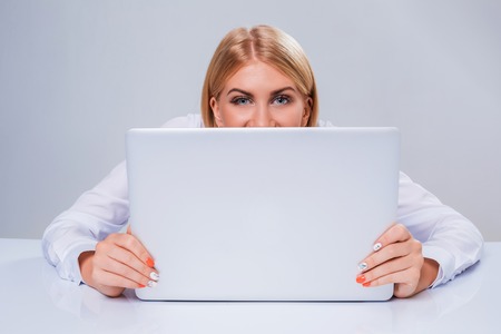 Young businesswoman working at laptop computer. hiding behind the monitorの写真素材