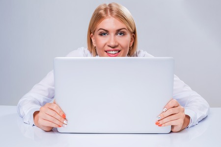 Young businesswoman working at laptop computer. hiding behind the monitor contented happy girlの写真素材