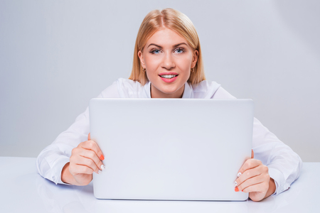 Young businesswoman working at laptop computer. hiding behind the monitor contented happy girlの写真素材