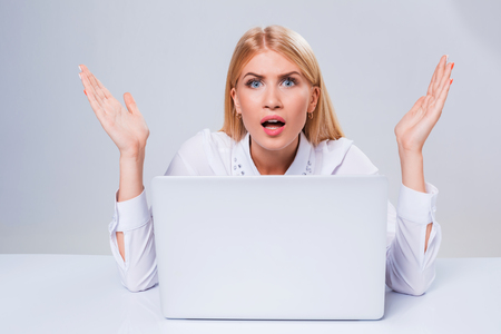 Young businesswoman working at laptop computer. hiding behind the monitor. frustrated, spiteful woman in shockの写真素材