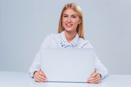Young businesswoman working at laptop computer. hiding behind the monitor contented happy girlの写真素材