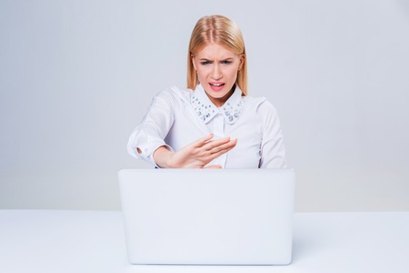 Young businesswoman working at laptop computer. hiding behind the monitor. frustrated, spiteful woman in shockの写真素材
