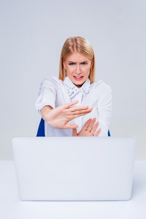 Young businesswoman working at laptop computer. hiding behind the monitor. frustrated, spiteful woman in shockの写真素材