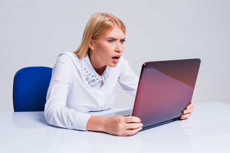 Young businesswoman working at laptop computer. pleasantly surprised dissatisfied girlの写真素材