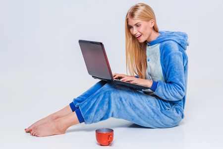 girl in pajamas with a laptop lying on the floor. studying or doing online shopping. work from home. Satisfied and smilingの写真素材