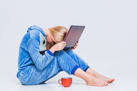 girl in pajamas with a laptop lying on the floor. studying or doing online shopping. work from home. tired woman, it does not workの写真素材