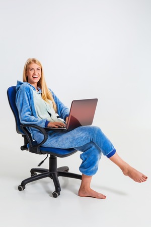 girl in pajamas with a laptop. studying or doing online shopping. work from home. girl smiling and happyの写真素材