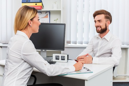 man and a woman being interviewed in the office. at table with computerの写真素材