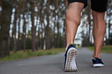 young athlete running in the forest, motion blur, feet close-upの写真素材