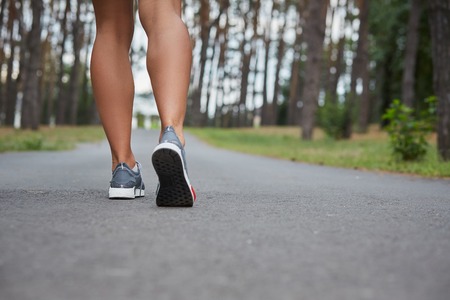Young woman running outdoors in a city park on. motion blurred image color toned image. feet close-upの写真素材