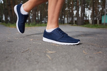 young athlete running in the forest, motion blur, feet close-upの写真素材