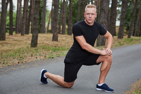 young athlete running in the forest, doing warm-up and stretchingの写真素材