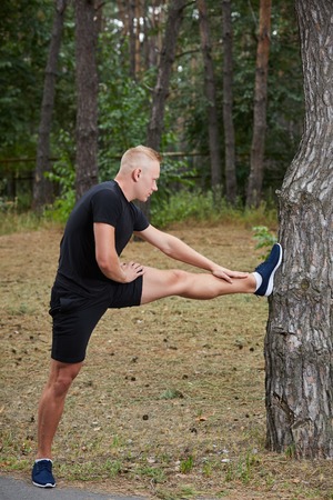 young athlete running in the forest, doing warm-up and stretchingの写真素材