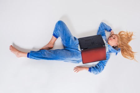 Young woman asleep with a laptop on the floor. Top view. She's in her pajamas and lies on her laptop