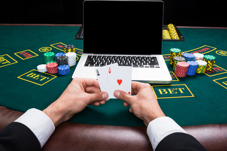 casino, online gambling, technology and people concept - close up of poker player with playing cards, notebook and chips at green casino table. first-person view. two aces, a winning combinationの写真素材