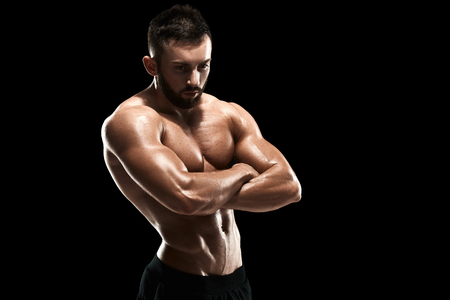 Muscular bodybuilder guy doing posing over black background.の写真素材