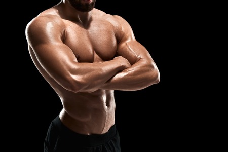 Muscular bodybuilder guy doing posing over black background. Close up