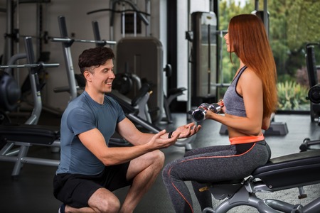 happy cutie athletic girl , execute exercise with dumb-bells and smile, in sport-hallの写真素材