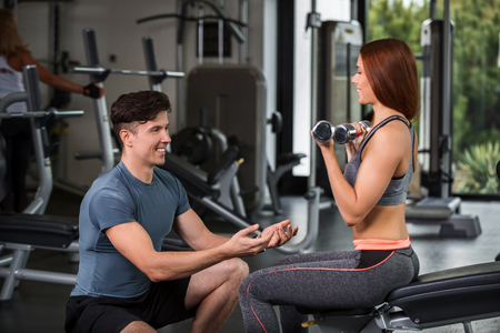 happy cutie athletic girl , execute exercise with dumb-bells and smile, in sport-hallの写真素材