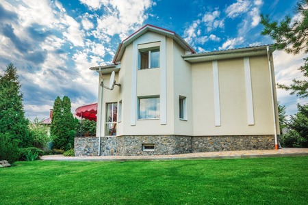 Beautiful house with a lawn. Facade of home with grass in the foreground. at sunset and sunriseの写真素材