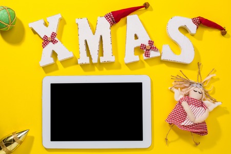 Smartphone with Christmas decorations. Christmas mock up template. View from above. yellow backgroundの写真素材