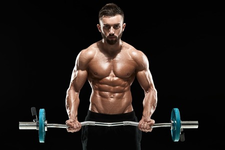 Close up of young muscular man lifting weights over dark backgroundの写真素材