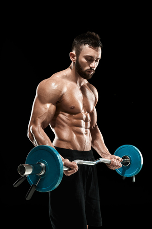 Close up of young muscular man lifting weights over dark backgroundの写真素材