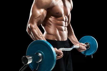 Close up of young muscular man lifting weights over dark backgroundの写真素材