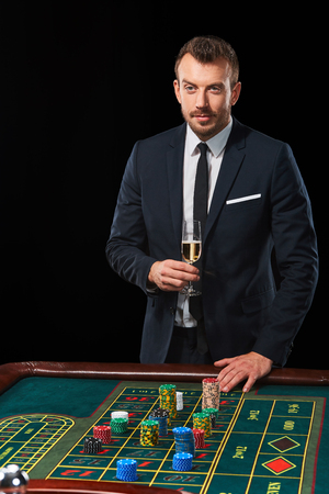 man in a suit playing roulette. addiction to gambling. In the hands of a glassの写真素材