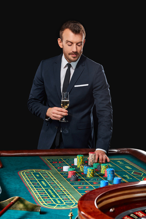 man in a suit playing roulette. addiction to gambling. In the hands of a glass. He bets chipsの写真素材
