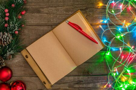 New Year and Christmas mokcup. notebook with Xmas lights on wooden background, space for your text, copyspace. from above. Holiday winter planning concept. Flat lay style.の写真素材