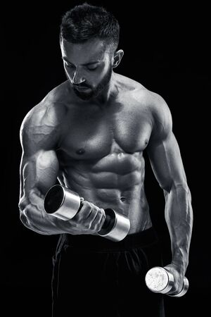 Muscular bodybuilder guy doing posing over black background. dumbbells in his hands. doing exercises. Black and white colorの写真素材