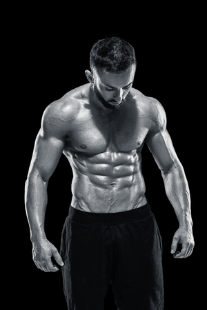Muscular bodybuilder guy doing posing over black background.. Black and white colorの写真素材