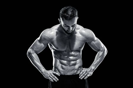 Muscular bodybuilder guy doing posing over black background.. Black and white color