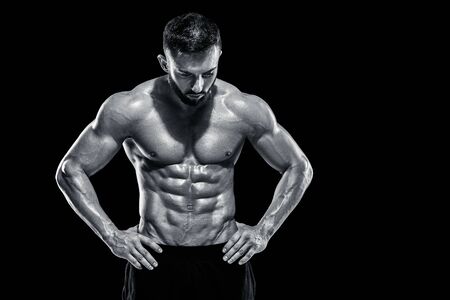 Muscular bodybuilder guy doing posing over black background. Black and white colorの写真素材
