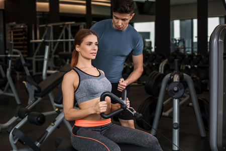 happy cutie athletic girl , with instructor execute exercises and smile, in sport-hall
