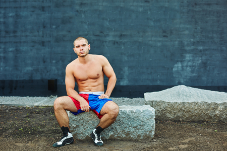The sportsman has a rest, sitting on a rock. He looks into the cameraの写真素材