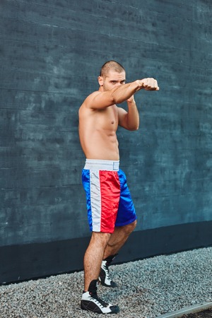 Boxer shorts in athletic training outdoors. He stands in a fighting stance. The young man works off a blowの写真素材
