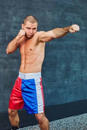 Boxer shorts in athletic training outdoors. He stands in a fighting stance. The young man works off a blowの写真素材