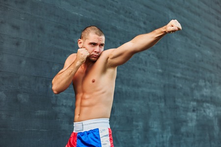 Boxer shorts in athletic training outdoors. He stands in a fighting stance. The young man works off a blowの写真素材