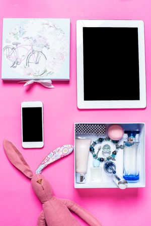Flat lay, top view, mock up girl's accessories on a pink background. bracelet, rabbit, toy, perfume, phone, tabletの写真素材