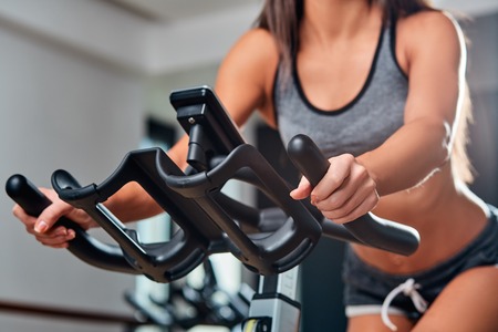 Sport young woman on a stationary bike in the gymの写真素材