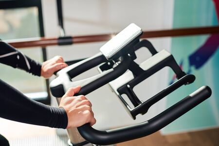 Strong female hand on a stationary bike in the gym