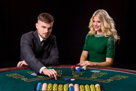 couple playing poker at the table. The blonde girl and a guy in a suit.の写真素材